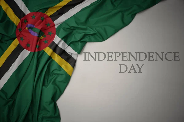 Waving colorful national flag of dominica on a gray background with text independence day. — Stock Photo, Image