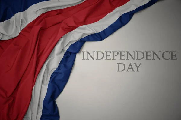 Integetett színes nemzeti zászló Costa Rica egy szürke háttér szöveges függetlenség napja. — Stock Fotó