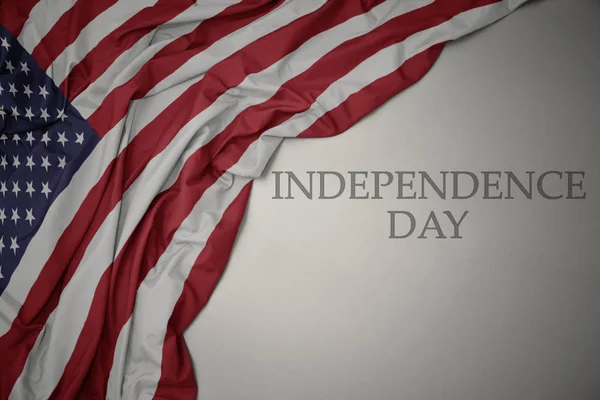 Κυματιστό πολύχρωμο εθνική σημαία των Ηνωμένων Πολιτειών της Αμερικής σε ένα γκρίζο φόντο με την ημέρα ανεξαρτησίας του κειμένου. — Φωτογραφία Αρχείου