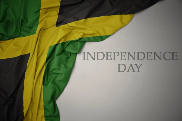 Acenando bandeira nacional colorida de jamaica em um fundo cinza com dia de independência de texto . — Fotografia de Stock