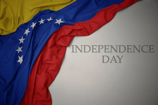 Waving colorful national flag of venezuela on a gray background with text independence day. — Stockfoto