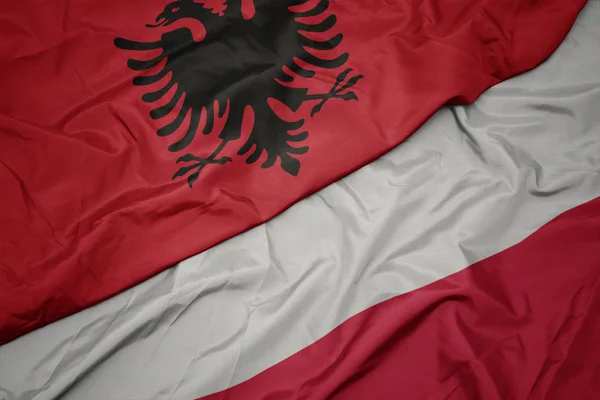 Sventolando bandiera colorata della Polonia e bandiera nazionale di albania . — Foto Stock