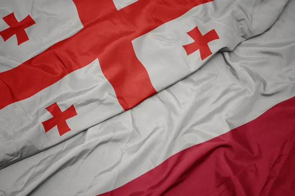 Acenando bandeira colorida de polônia e bandeira nacional de georgia . — Fotografia de Stock