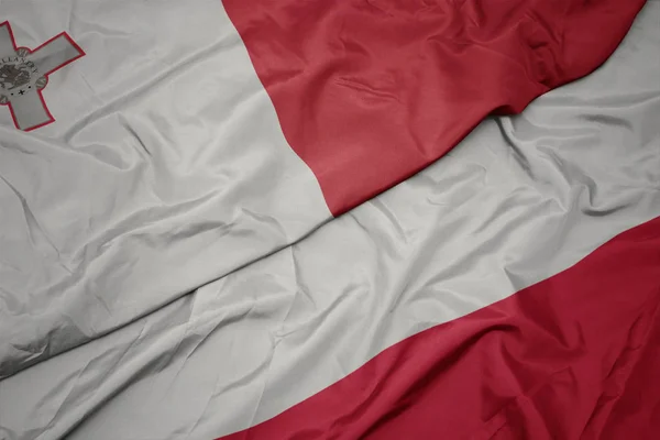 Ondeando colorida bandera de Polonia y bandera nacional de Malta . — Foto de Stock