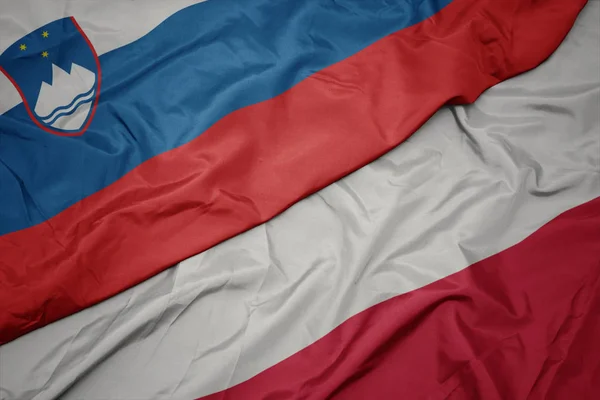Mávající barevná vlajka Polska a národní vlajky Slovinska. — Stock fotografie