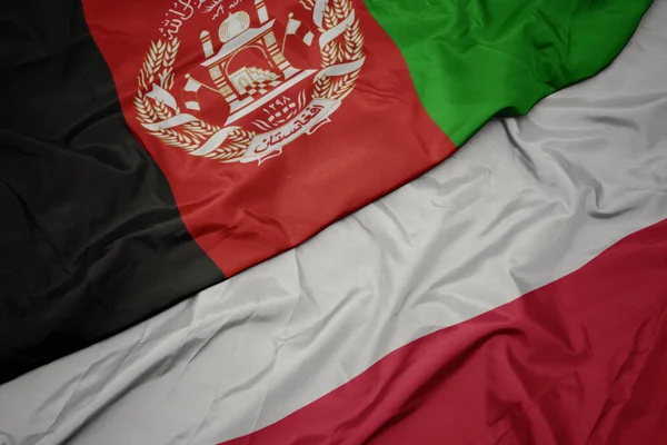 Zwaaiende kleurrijke vlag van Polen en de nationale vlag van Afghanistan. — Stockfoto