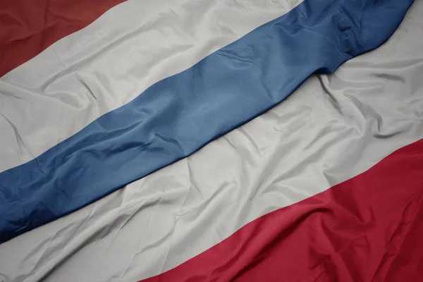 Falujące kolorowe flagi Polski i flagi narodowej Luksemburga. — Zdjęcie stockowe