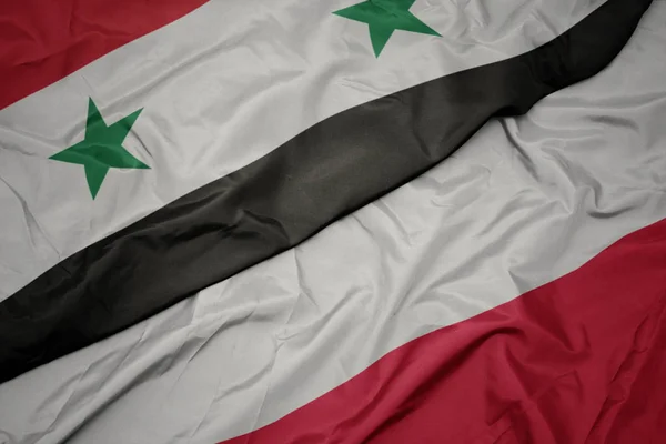 Zwaaiende kleurrijke vlag van Polen en de nationale vlag van Syrië. — Stockfoto