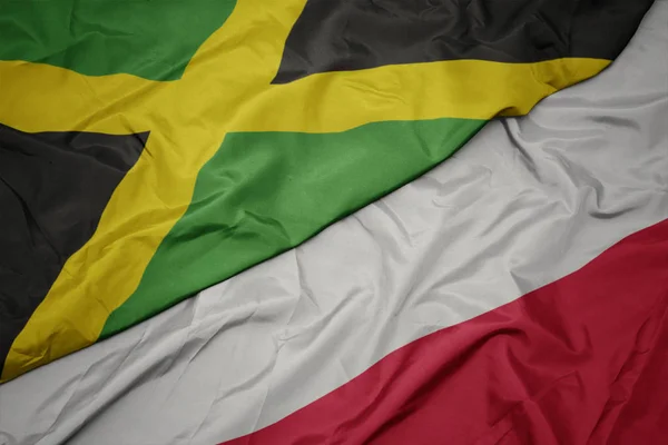 Ondeando colorida bandera de Polonia y bandera nacional de jamaica . — Foto de Stock