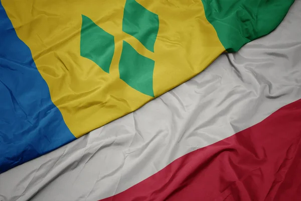 Zwaaiende kleurrijke vlag van Polen en de nationale vlag van Saint Vincent en de Grenadines. — Stockfoto