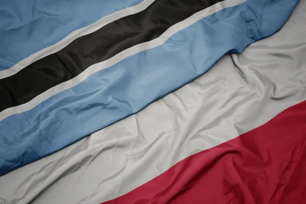 Ondeando colorida bandera de Polonia y bandera nacional de Botswana . — Foto de Stock