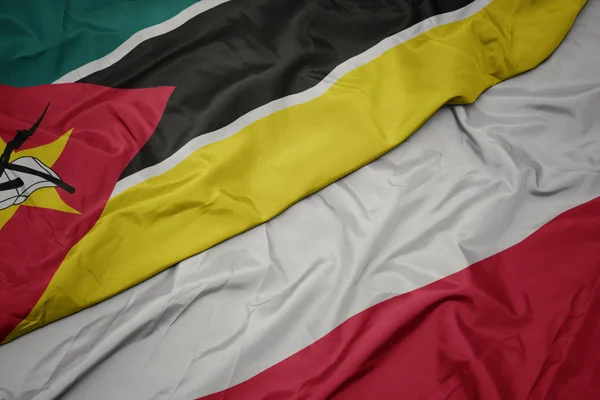 Acenando bandeira colorida de polônia e bandeira nacional de moçambique . — Fotografia de Stock
