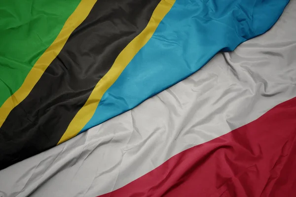 Ondeando colorida bandera de Polonia y bandera nacional de Tanzania . —  Fotos de Stock