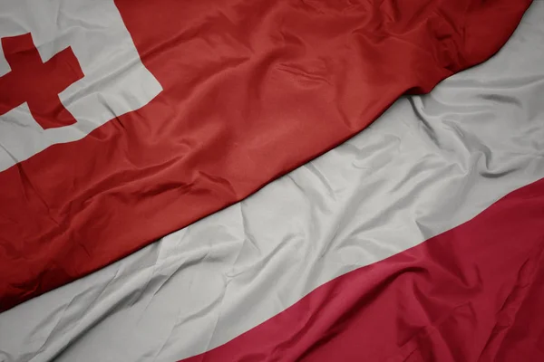 Ondeando colorida bandera de Polonia y bandera nacional de Tonga  . —  Fotos de Stock