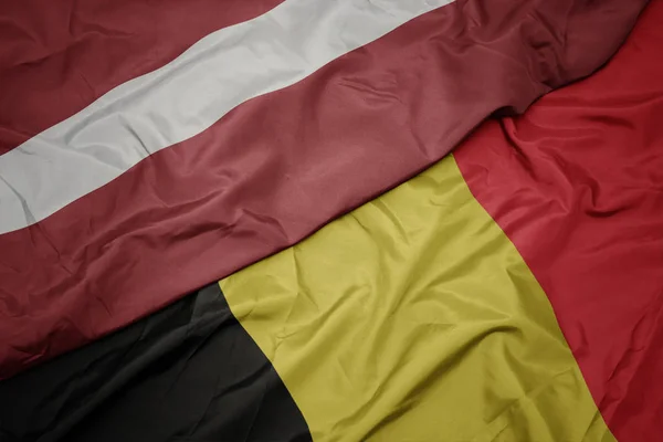 Ondeando colorida bandera de belgium y bandera nacional de latvia . — Foto de Stock