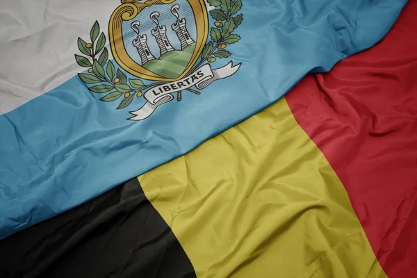 Waving colorful flag of belgium and national flag of san marino. — Stock Photo, Image