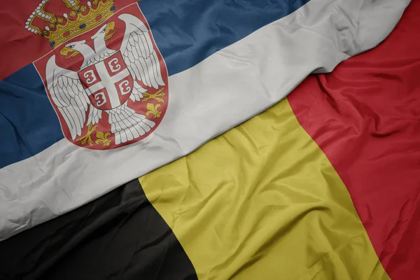 Falująca kolorowa flaga Belgii i flaga narodowa Serbii. — Zdjęcie stockowe