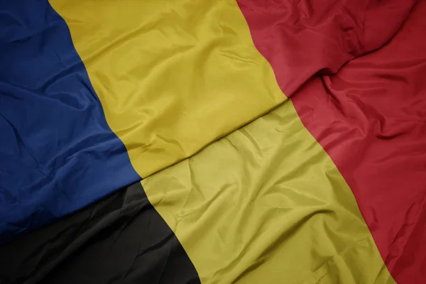 Ondeando colorida bandera de belgium y bandera nacional de romania . — Foto de Stock