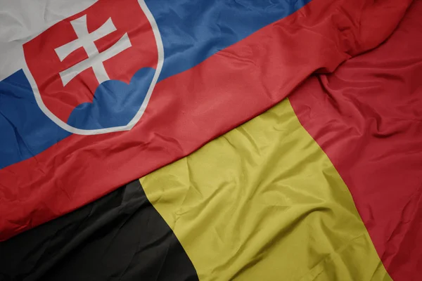 Acenando bandeira colorida da Bélgica e bandeira nacional da Eslováquia . — Fotografia de Stock