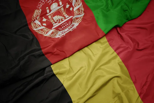 Ondeando colorida bandera de Bélgica y bandera nacional de Afganistán . — Foto de Stock