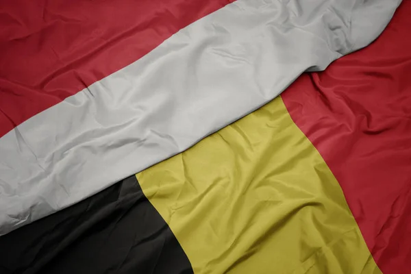 Sventolando bandiera colorata di belgio e bandiera nazionale di indonesia . — Foto Stock
