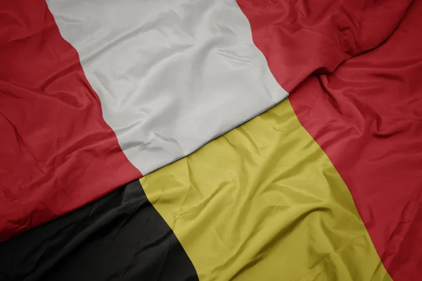 Ondeando colorida bandera de belgium y bandera nacional de perú . — Foto de Stock