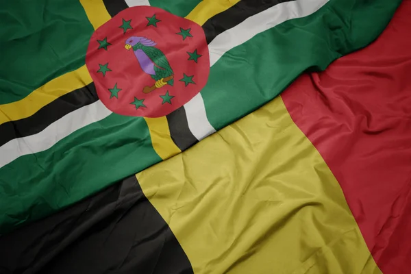 Schwenken bunte Flagge Belgiens und Nationalflagge Dominicas. — Stockfoto