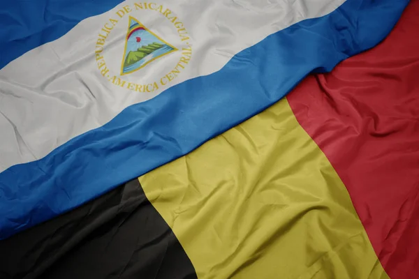 Ondeando colorida bandera de belgium y bandera nacional de nicaragua . —  Fotos de Stock