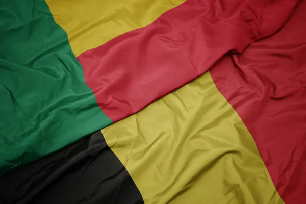Waving colorful flag of belgium and national flag of benin. — Stock Photo, Image