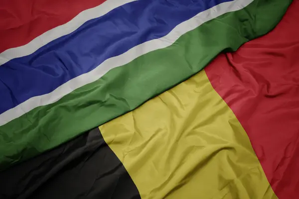 Acenando bandeira colorida da Bélgica e bandeira nacional da Gâmbia . — Fotografia de Stock