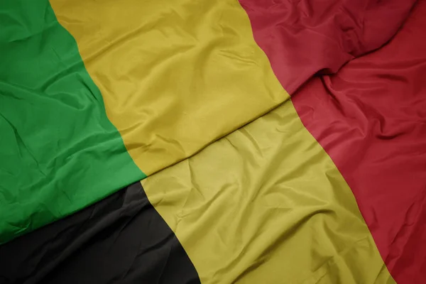 Machanie barwną flagą Belgii i flagą narodową Mali. — Zdjęcie stockowe