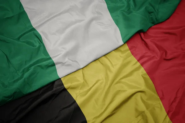 Machanie barwną flagą Belgii i flagą narodową Nigerii. — Zdjęcie stockowe
