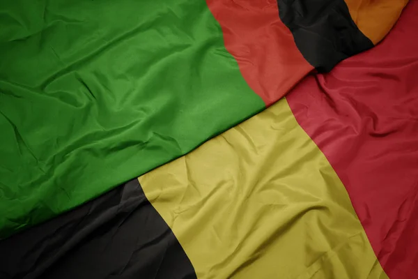 Acenando bandeira colorida da Bélgica e bandeira nacional da Zâmbia . — Fotografia de Stock