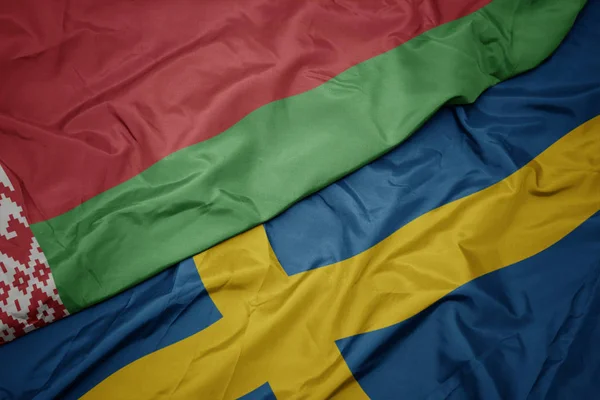 Sventolando bandiera colorata della Svezia e bandiera nazionale della Bielorussia . — Foto Stock