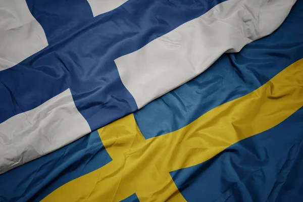 Zwaaiende vlag van Zweden en nationale vlag van Finland. — Stockfoto