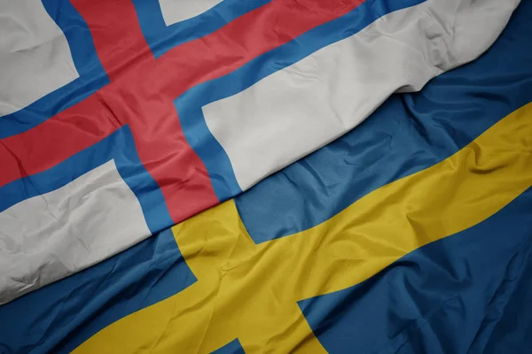 Machanie kolorową flagą Szwecji i flagą narodową Wysp Owczych. — Zdjęcie stockowe