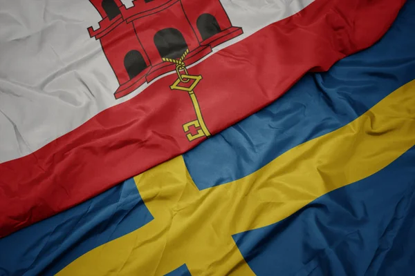 Agitant drapeau coloré de la Suède et drapeau national de gibraltar . — Photo