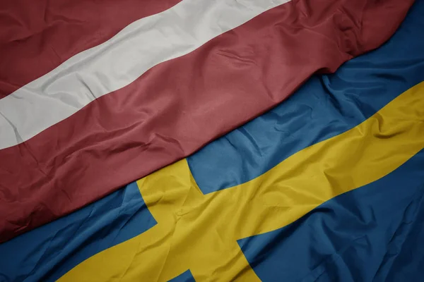 Размахивая красочным флагом Швеции и национальным флагом Латвии . — стоковое фото