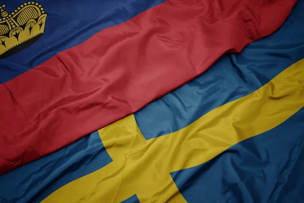 Machanie kolorową flagą Szwecji i flagą narodową Liechtensteinu. — Zdjęcie stockowe