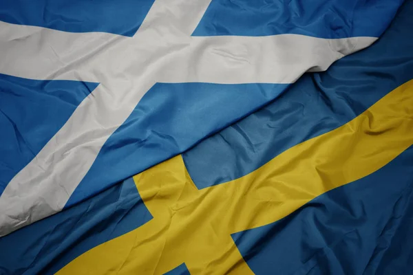 Machanie kolorową flagą Szwecji i flagą narodową Szkocji. — Zdjęcie stockowe