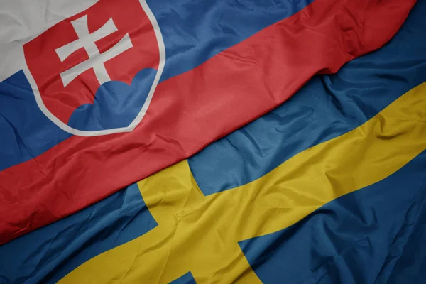 Acenando bandeira colorida da Suécia e bandeira nacional da Eslováquia . — Fotografia de Stock