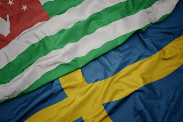 Sventolando bandiera colorata della Svezia e bandiera nazionale dell'abkhazia . — Foto Stock