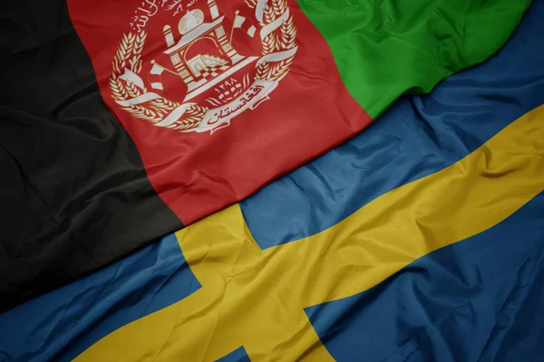 Ondeando colorida bandera de Suecia y bandera nacional de Afganistán . — Foto de Stock