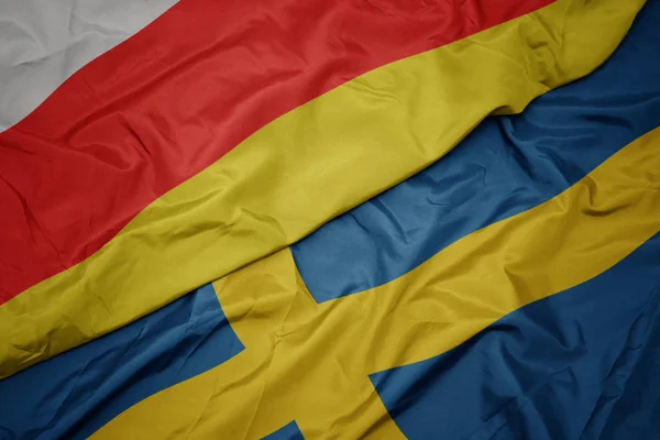 Melambaikan bendera berwarna-warni sweden dan bendera nasional dari selatan ossetia . — Stok Foto