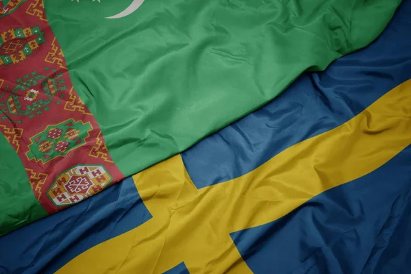 Sventolando bandiera colorata della Svezia e bandiera nazionale del turkmenistan . — Foto Stock