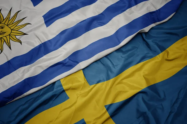 Waving colorful flag of sweden and national flag of uruguay. — Stock Photo, Image
