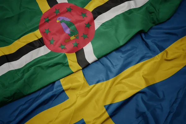 Acenando bandeira colorida da Suécia e bandeira nacional da Dominica . — Fotografia de Stock