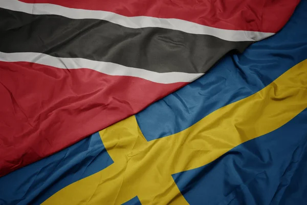 Sventolando bandiera colorata di bandiera svedese e nazionale di trinidad e tobago . — Foto Stock