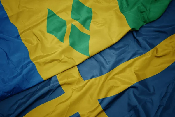 Machanie kolorową flagą Szwecji i flagą narodową świętego Vincenta i granatów. — Zdjęcie stockowe