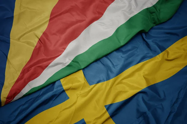 Mávání barevnou vlajkou švédské a národní vlajky seychel. — Stock fotografie